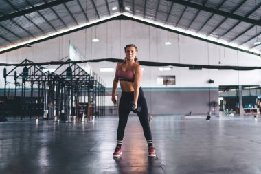 Spor salonunda egzersiz yaparken ağırlık kaldırmak ve antrenman yapmak için dambıl kullanan beyaz kadın. Kas şeklindeki güçlü kadın spor ekipmanlarıyla egzersiz yapıyor.