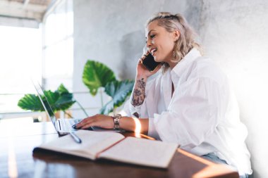 Milenyum sarışın kadın, akıllı telefondan ararken bilgi almak için netbook teknolojisini kullanıyor. Yetenekli kadın blogcu, cep telefonu uygulaması üzerinden ararken e-posta mesajlarını kontrol ediyor.