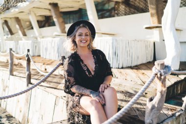 20 'li yaşlardaki mutlu beyaz kadın, turistik gezi sırasında kumsalda dinlenirken kameraya gülümsüyor, siyah bikini mayo giymiş neşeli bayan yüzücü Endonezya' da güneşlenirken eğleniyor.