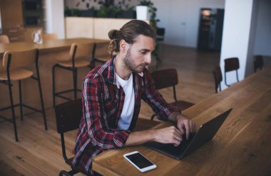 Modern dizüstü bilgisayarda uzaktan çalışan Millennial erkek bilişim uzmanı grafik tasarım için medya uygulaması kullanıyor, yetenekli bir adam dijital ağ kitabına web uygulaması yüklerken içeriği tarıyor