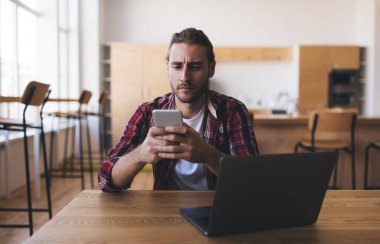 Bilgisayarı kontrol eden ciddi bir erkek bilişim uzmanı internet haberlerinde kafası karışmış, dijital netbook okuyabilen mobil yayın yapan bir adam modern akıllı telefon cihazından e-posta aldı.