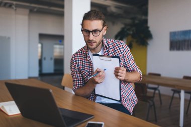 Kafkasyalı adamın, modern dizüstü bilgisayar teknolojisi konulu uzak konferans sırasında evrak ve organizasyon planlarını analiz etmek için online semineri var.