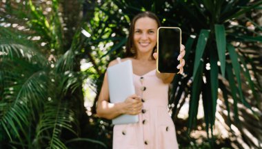 Bilgisayarlı bulanık kadın dijital göçebe web sitesi metniniz için kopyalama alanı olan akıllı telefon teknolojisini gösteriyor. Cep telefonu reklamları sırasında cep telefonu cihazını tutan kadın model.