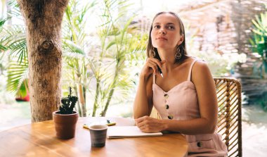 Sokak kafesinde yayın içeriği planladığı için ders kitabı olan düşünceli bir kadın gazeteci. Kafkasyalı kadın bilgi eğitimi için metin fikirlerini düşünüyor.