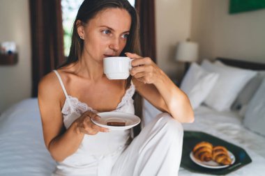 Kafkasyalı bir kadın rahat yatağında dinleniyor. Uyandıktan sonra lezzetli sabah kapuçinosu içiyor. Beyaz ipek gecelikli, elinde çay fincanı tutan genç bir kadın hafta sonunu lüks bir otelde eğlenmek için geçiriyor.