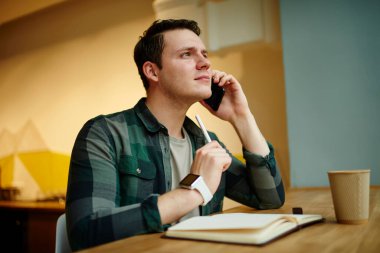 Genç, beyaz bir adam cep telefonuyla arıyor. Elinde netbook ile masada otururken. Serbest çalışan uzaktan kumanda