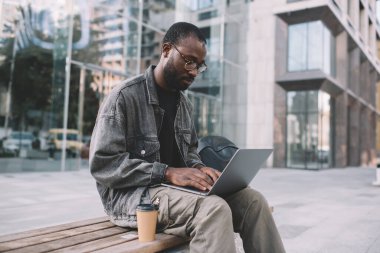 Modern dizüstü bilgisayarda medya uygulaması ile grafik tasarımı düzenlemek için klasik göz gezdirme web sitesinde yetenekli erkek programcı, binyıllık Afro-Amerikan yazılım geliştiricisi