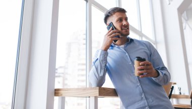 Sosyal hizmetleri aramak ve kablosuz bağlantıyı tartışmak için cep telefonu uygulamasını kullanan akıllı girişimci kahve molasında cep telefonu sohbeti ve iletişim kuran milenyum adamı.