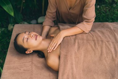 Terapi süresince gergin cilt için Tayland masajı yapan genç bir kadın - dingin spa tedavisi konsepti, Asyalı bir kadın profesyonel kozmetik uzmanı ve masörle pazar günleri kaplıcada eğleniyor.