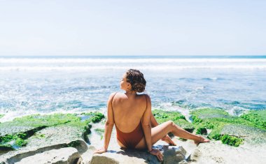 Mayo giymiş, plajda güneşlenen genç bir kadın. Tatillerde dinlenmenin ve sakinliğin tadını çıkaran kadın turist. Güneşten korunmak için cilt koruması çok önemlidir.