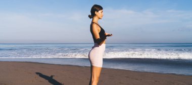 Kıyı şeridinde yoga yapan beyaz tenli kadın sağlıklı yaşam tarzına ve sağlığına kavuşuyor spor eşofmanlı sakin kadın Asya 'da farkındalık ve aydınlanma için vakit geçiriyor.