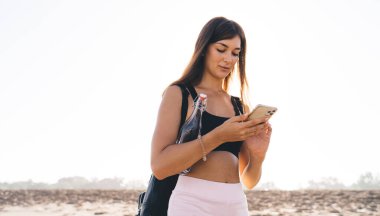 Sosyal ağlarda sohbet etmek ve mesajlaşmak için hücresel aygıt kullanan çekici kadın seyahat blogcusu, günlük giyimli genç beyaz kız web içeriğini taramak için 4G kablosuz ağa bağlanıyor