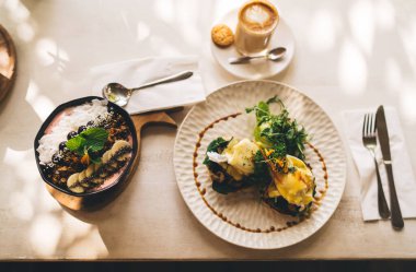 Kahvaltıda meyve ve granola ile sağlıklı yaşam tarzını sürdürmek için nefis sabah yemeklerinin üst görüntüsü, taze organik malzemelerle hazırlanmış ev yapımı lezzetli yiyeceklerle dolu tabaklar.