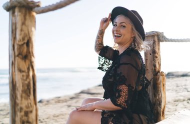 Hafta sonu plajda güneşlenmek için kameraya gülümseyen neşeli kadın portresi, mutlu beyaz kadın artı beden modelleri deniz kıyısında bronzlaşırken pozitifliğin tadını çıkarıyor.