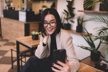 Milenyum Asyalı güzel bir kız kafede akıllı telefondan arıyor. Masada oturan, gülümseyen esmer, gözlüklü genç bir kadın. Dinlenmek, boş zaman ve boş zaman kavramı. Modern kadın yaşam tarzı