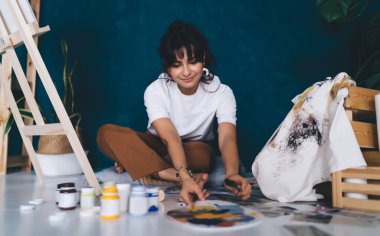 Çekici genç bayan ressam resim çiziyor ve hobisinin rahatlatıcı sürecinden zevk alıyor. Yaratıcı ve yetenekli esmer kadın sehpada resim yaratıyor. Petrolle çizim yapmayı öğrenmek