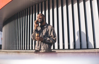 Positif cep telefonu iletişimi sırasında gülümseyen mutlu Afrikalı Amerikalı hipster adam. Kahveli neşeli erkek milenyumu. Akıllı telefon cihazıyla arama ve arama yapmak için uygulama kullanıyor.