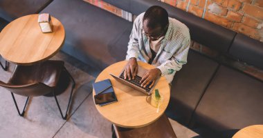 İnternet sitelerinde çalışan dizüstü bilgisayarda yazan koyu tenli erkeğin üst görünümü, sosyal ağlarda iletişim kuran yetenekli yazılım programcısı, netbook üzerinden web tasarımı oluşturan