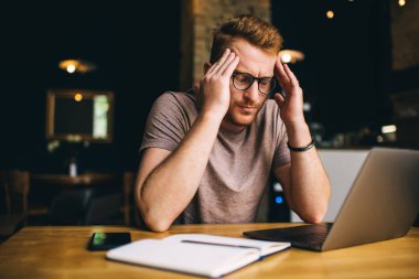 Düşünceli genç adam çalışırken dizüstü bilgisayarda dikkatlice webinar izliyor. Kızıl saçlı erkek serbest yazar düşünceli bir şekilde Netbook 'ta proje çözümü üzerinde çalışıyor. Kafkas öğrenci eğitimi online