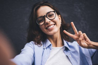 Cep telefonu uygulamasında selfie çekerken kameraya poz veren bin yıllık kadın etkileyicinin portresi. Sosyal ağ fotoğrafı, blog yazarken kendi fotoğrafını çeken genç bir kadın. Çevrimiçi Video çağrısı