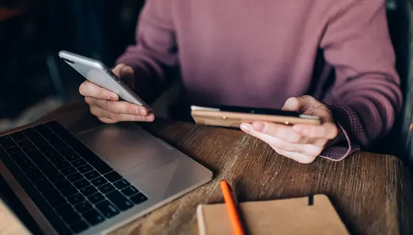 stock image Cropped software developer updating computer settings using cellphone application for checking web details, unrecognizable man browsing wireless publication while creating content plan for blog