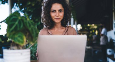 Uzaktan çalışan, modern dizüstü bilgisayar teknolojisi olan ve serbest iş yaparken poz veren bin yıllık kadın blogcu için kameraya bakan yetenekli Kafkas dijital göçebe portresi