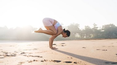 Eşofmanlı çıplak ayaklı kadın yogi ABD 'de okyanus kenarında hatha sporu yapıyor. Sağlıklı yaşam tarzını koruyor. Beyaz kadın yoga pozu veriyor.