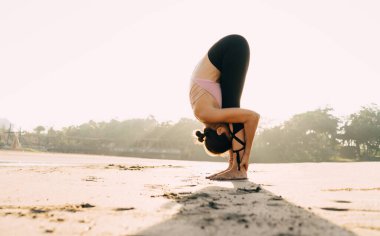 Kafkas kadın Yogi 'nin sabah kıyı şeridinde vücut ısısı esnerken yan görüntüsü. Eşofmanlı genç bir kadın vücut pozitifliğine ulaşmak için Asana' da sağlıklı yaşam tarzının tadını çıkarıyor.