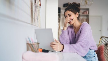 Genç milenyum kadın serbest video konferansında dizüstü bilgisayarla masaya oturuyor. Uzaktan çalışmak için taşınabilir netbook kullanırken hocasıyla çevrimiçi öğrenmekten mutlu olan kız öğrenci.