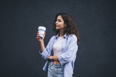 Yarım boy portre, yanında sıradan giyinmiş bir kadın fotokopi arkaplanının yanında bir fincan kahve götürüyor. Milenyum modasına uygun bir kadın yeniden kullanılabilir bardaktan mocha içiyor.