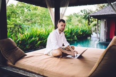 Bilgisayar teknolojisi olan beyaz adamın portresi, medya uygulaması üzerinden uzaktan çekim yaptığı için kameraya bakıyor, netbook 'u olan milenyum bağımsız metin yazarı dijital göçebe yaşam tarzını koruyor