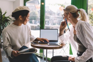 Web yayınını tartışan mutlu kadın serbest çalışanlar fotokopi alanı ile birlikte dizüstü bilgisayara baktılar, boş netbook teknolojisi olan milenyum blogcuları ağlarda metin reklamlarını okuyorlar