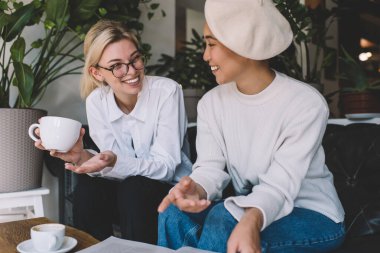 Neşeli Asyalı ve Kafkas kadın arkadaşları şık kıyafetler giyip, kahve toplantılarında bilgi tartışıyor ve gülüyorlar. Neşeli hipster kızlar içeride pozitif iletişimin keyfini çıkarıyorlar.