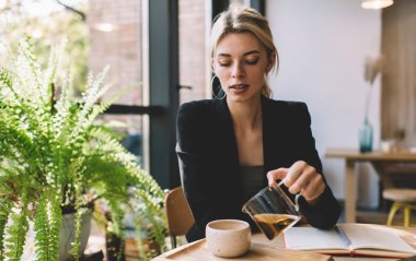 Gündüz vakti kafenin içinde şık giyinmiş güzel bir kadın çay bardağına çay dolduruyor. Eğitimli, Kafkas kökenli, ders kitabı harçlığı olan genç bir kadın, sıcak içecek içmek için mola veriyor.