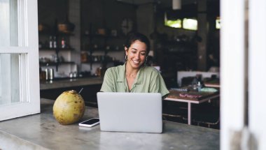 Genç İspanyol kadın dizüstü bilgisayarda çalışıyor ve bir fincan kahveyle birlikte çalışıyor. Netbook 'ta gülümseyen serbest çalışan kadın web sitesi. Öğrenci webinar öğreniyor, bilgi okuyor