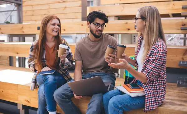 Üç günlük giyinmiş arkadaş dışarıda otururken kahve içip sohbet ediyorlar. Kampüste toplanıp sohbet eden bir grup öğrenci. Birlikte vakit geçirmek.