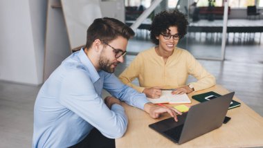 İş kadını ve iş adamı dizüstü bilgisayardan bir şey izliyor. İş birliği ve takım çalışması kavramı. Genç Kafkasyalı milenyum insanları ofiste masa başında. Modern başarılı insanların fikirleri.