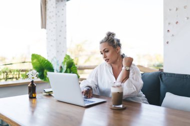 Terasta uzaktan çalışan modern netbook bilgisayarında webinar video izleyen güzel beyaz kadın, bin yıllık kadın bilişim uzmanları dijital dizüstü bilgisayar teknolojisi hakkında haberler aldılar.