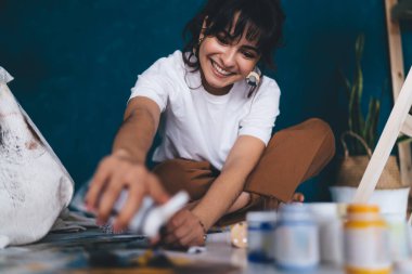 Çekici genç bayan ressam resim çiziyor ve hobisinin rahatlatıcı sürecinden zevk alıyor. Yaratıcı ve yetenekli esmer kadın sehpada resim yaratıyor. Petrolle çizim yapmayı öğrenmek