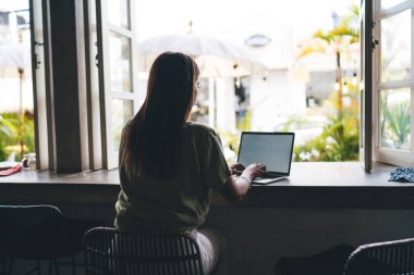 Genç bir kadın dizüstü bilgisayarda çalışıyor masada oturuyor, klavyede daktilo yazıyor. İnternet sitesinde serbest çalışan bir kadın internet sitesi. Webinar 'da öğrenen öğrenci, V reklamları için boş ekranı taklit edin.