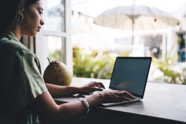 Genç bir kadın dizüstü bilgisayarda çalışıyor masada oturuyor, klavyede daktilo yazıyor. İnternet sitesinde serbest çalışan bir kadın internet sitesi. Webinar 'da öğrenen öğrenci, reklam için boş ekranı taklit edin 
