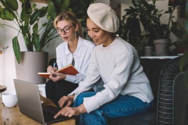 Asyalı ve Kafkasyalı kadın metin yazarları, içerik fikirleri oluşturmak için birlikte çalışma alanında yapılan beyin fırtınası sırasında 4G kablosuz ağ kullanarak modern dizüstü bilgisayarda web sayfalarına göz atıyorlar.