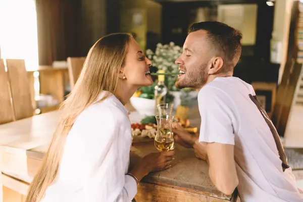 stock image Happy Caucasian couple in love having fun during brunch meal at terrace, young male and female with white wine eating one asparagus bean togetherness - sharing food while bonding and communicating