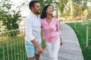 Mutlu, çoklu etnik çeşitlilikteki çift yaz aylarında parkta birlikte yürürken gülümseyip bakışlarını kaçırıyor.