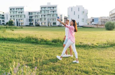 Sevgili sevgili kız ve erkek arkadaşın el ele tutuşup gökyüzüne hayranlık duyması randevuda çimenli çayırlarda birlikte yürürken