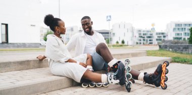 Mutlu Afro-Amerikan çift yan yana oturmuş, keyifli keyifle konuşurken birbirlerine bakıyorlar.