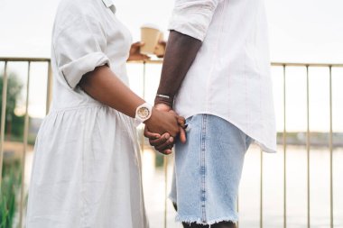 Yüzü olmayan Afro-Amerikan kadın ve erkek yazın el ele tutuşurken kıyıya yakın dururlar.