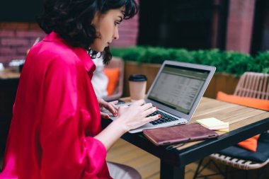 Pembe bluzlu serbest çalışan, masa başında oturan ve sokak kafesindeki uzak iş projesinde çalışan kadın.