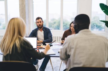 Çok ırklı modern iş arkadaşları şık gündelik giysiler içinde yeni bir iş kurma ve açık çatı katında konuşma konularında takım olarak işbirliği yapıyorlar.