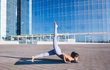 Esnek sporcu kadın şehir merkezinde sabah antrenmanı sırasında denge ve esneklik egzersizleri yapıyor. İnce vücutlu aktif Asyalı kadın yogi sağlıklı yaşam tarzından zevk alıyor.